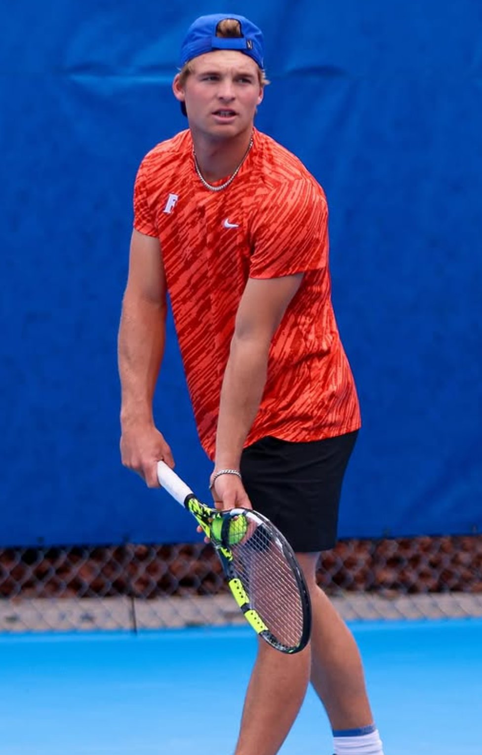 Kevin Edengren preparing to serve in orange Gators kit