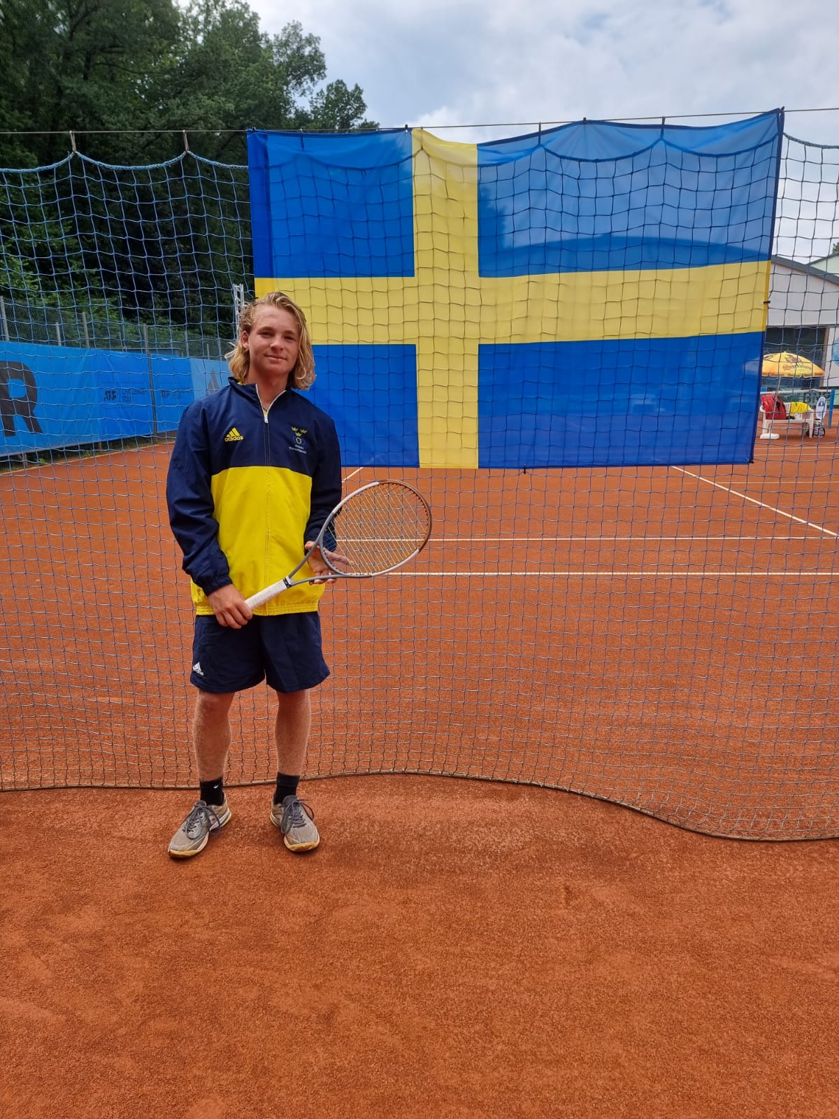 Kevin Edengren representing Team Sweden on clay court with Swedish flag